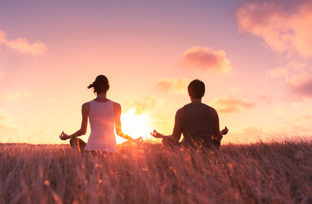 Couple meditating at sunset